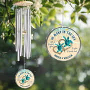 Wind chime with turtle design and personalized text hanging among green leaves.