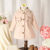 Pink coat on a mannequin with flowers and a handbag in the background