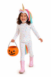 Child in a unicorn costume with a rainbow horn, holding an orange pumpkin bucket on a white background